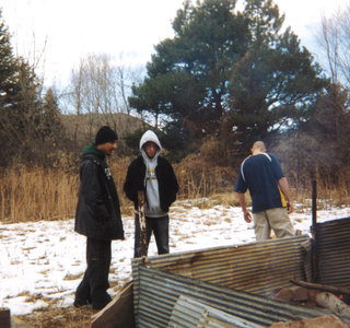 A group of men standing around a fire at sweat lodge and supporters reunion in 2002