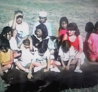 Group of kids sitting and learning in the grass